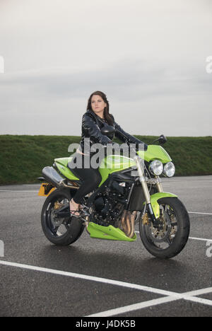 Fille brune sur une Triumph Street Triple moto dans une voiture aprk Banque D'Images