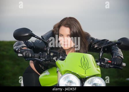 Fille brune sur une Triumph Street Triple moto dans une voiture aprk Banque D'Images