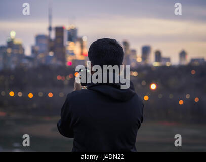 Un homme en cliquant sur photo avec téléphone et admirant soleil sur Toronto Skyline Banque D'Images