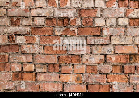 Fragment de mur de briques rouges vieillies à la texture ou à l'arrière-plan. Banque D'Images