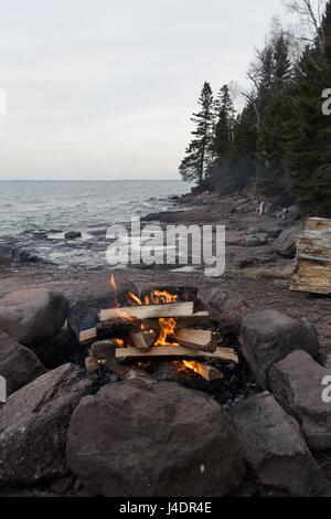 Un feu de camp à côté de Lac Supérieur au crépuscule. Banque D'Images