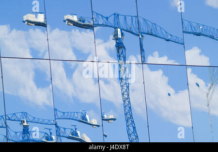 Distrorted et les images floues de grues de construction et de travail reflète dans de grandes fenêtres du bâtiment Banque D'Images