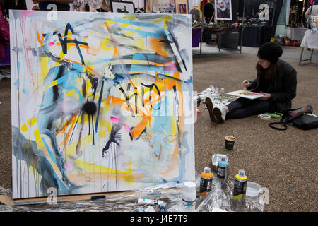 Londres, Royaume-Uni. 12 mai 2017. Derrière Joanna Gilbert's art abstrait artiste Saskia van Geest est assis sur le plancher. Vieux Marché de Spitalfields's official charity - Coeurs en harmonie, a accueilli l'événement de toute une journée de "l'Art Bat'. Les artistes se sont réunis et ont créé des œuvres devant un auditoire, en compétition pour le "Prix de l'Art Bat'. L'organisme de bienfaisance coeurs en harmonie est la collecte de fonds pour aider à lutter contre les maladies du coeur à travers l'art et de manifestations musicales, et tous les fonds recueillis seront remis à la maladie de coeur dans les hôpitaux et à la recherche. Photo : Images éclatantes/Alamy Live News Banque D'Images