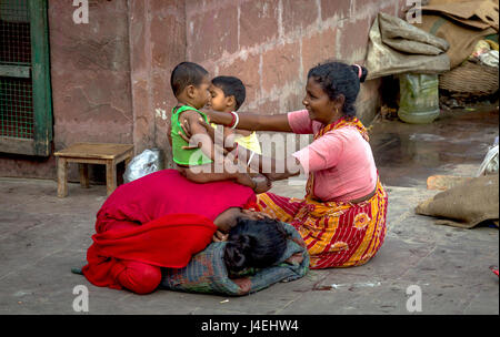 Le bonheur dans la pauvreté. Une mère caresse son enfant bébé fille sur une rue chaussée à Kolkata, Inde. Banque D'Images