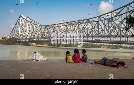 Les enfants de la rue apprécier la vue de l'Howrah Bridge à partir de la banque de la rivière Hooghly mallick à ghat, Kolkata, Inde. Banque D'Images