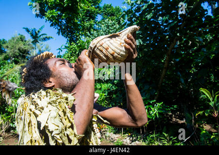 L'homme qui souffle dans une coquille géante, Ekasup Village culturel, Efate, Vanuatu, Pacifique Banque D'Images