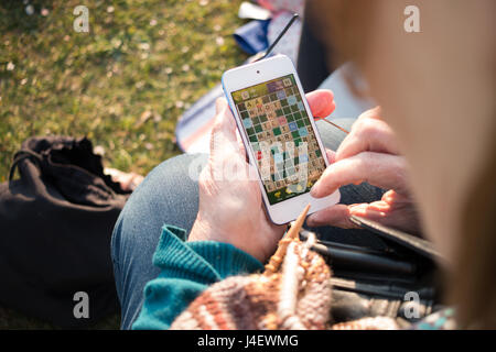 Une femme plus âgée jouant au Scrabble sur un smartphone. Banque D'Images