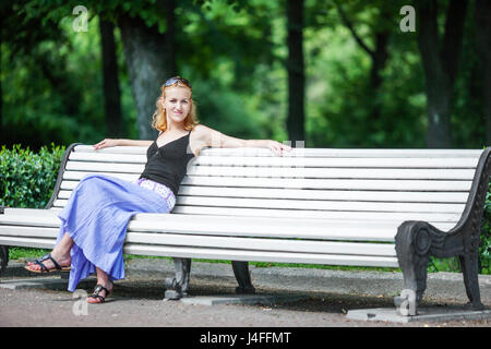 Jeune femme blonde assise seule sur un banc Banque D'Images