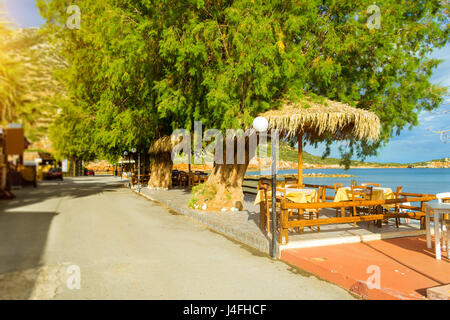 Tables avec parasols en chaume sont sur la route de beach café sur le front de mer. Livadi Beach dans la baie de la mer village Resort Bali en mai. Bali, Crète, Gree Banque D'Images