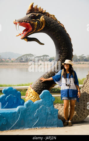 Voyageurs femme thaïlandaise visiter et qui pose pour prendre une photo avec la statue de naga noir à Mae Khong riverside de Chiang Khan pour l'écriture de blog le 21 février, 201 Banque D'Images