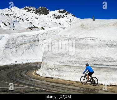 Biker riding entre des murs de neige sur la route du col de l'ensemble du col du Gothard, St, St Col du Gotthard, Canton du Tessin, Suisse Banque D'Images