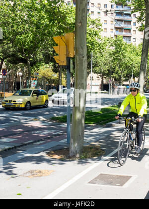Un cycliste féminine équitation son vélo sur une piste cyclable sur l'Avinguda Diagonal bordée, Barcelone, Espagne Banque D'Images