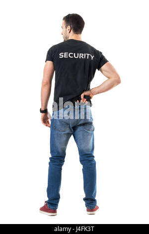 Vue arrière de l'alerté flic infiltré ou agent de sécurité reaching hand gun attaché à la ceinture. La pleine longueur du corps portrait isolé sur fond blanc Banque D'Images