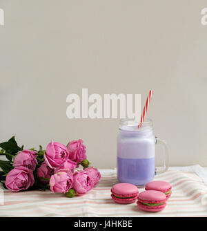 Café pourpre en pot Mason Tasse stylisée avec ses macarons et les roses et une décoration colorée. Lait frappé aux bleuets. Café Unicorn. L'alimentation Unicorn Banque D'Images