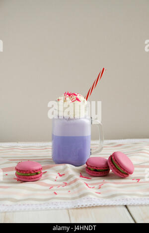 Café pourpre en pot Mason Tasse stylisée avec ses macarons et une décoration colorée. Lait frappé aux bleuets. Café Unicorn. L'alimentation Unicorn Banque D'Images