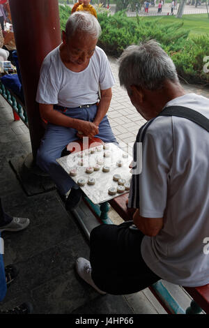 Beijing, Chine - 20 juin 2011 : Deux joueurs d'échecs chinois messieurs assis sur une rampe en bois profondément dans la concentration. Banque D'Images