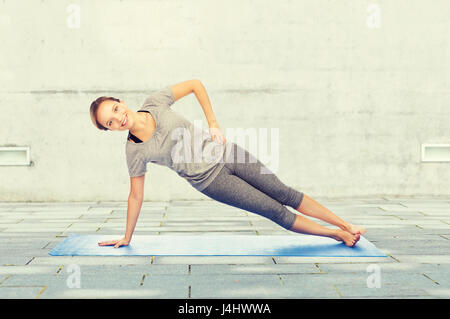 Femme faisant yoga Yoga à côté planche sur mat Banque D'Images