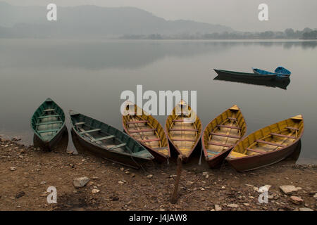 Bateaux en bois vert et jaune sur la rive du lac, Feva l'eau calme du lac comme un miroir reflète les montagnes bleues à l'arrière-plan, Pokhara Banque D'Images