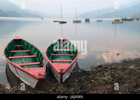 Deux bateaux de couleurs : blanc éclatant et vert et rouge à l'intérieur, placée sur la rive du lac, dans le contexte de nombreux autres bateaux, l'aube, Pokhara, Banque D'Images