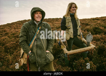 Les fauconniers Steve et Emma Ford posant avec leurs faucons et les chiens de chasse dans les landes à Gleneagles, en Écosse. Derek Hudson / Alamy Stock Photo Banque D'Images