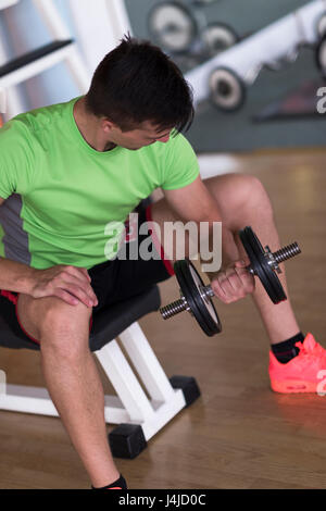 Young handsome man working out with dumbbells dans une salle de sport Banque D'Images