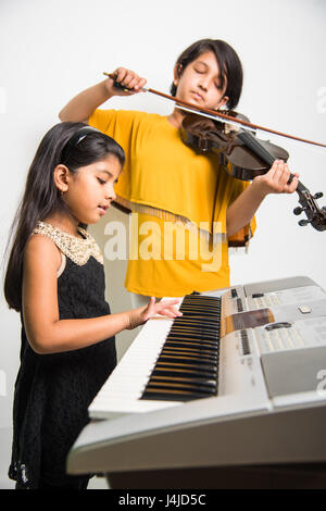 enfants et concept de musique - petites filles indiennes jouant des instruments de musique comme le piano, le clavier ou le violon Banque D'Images