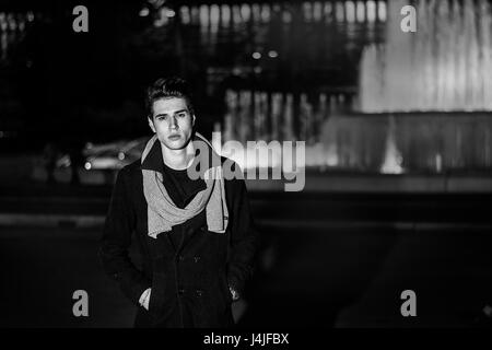 Jeune homme à l'extérieur assis près d'une grande fontaine Banque D'Images