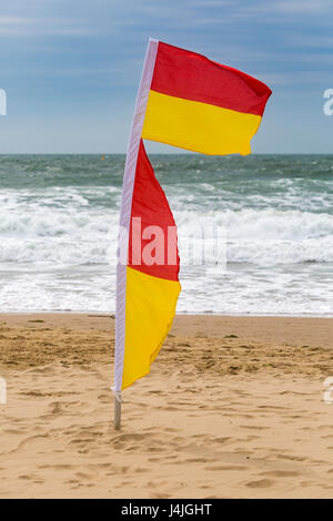 Drapeaux rouge et jaune indiquant zone sécuritaire de nager au bord de la mer, sur la plage de Bournemouth en Avril Banque D'Images