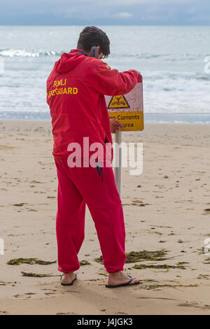 Sauveteur RNLI fixant les forts courants dans ce domaine signer au bord de la mer, sur la plage de Bournemouth en Avril Banque D'Images