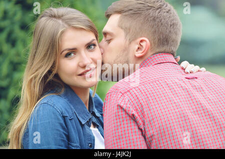 Jeune fille belle à regarder pendant que l'appareil photo d'être embrassé par son petit ami. Close up portrait. L'amour, relation, famille et personnes concept - smiling Banque D'Images