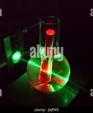 Et laser de rubis. Expérience avec un faisceau laser vert utilisé pour induire une luminescence rouge dans une tige de rubis artificiels. Le faisceau laser est aussi en passant par l'eau dans lequel la tige est partiellement submergé. Rubis synthétique est utilisé pour rendre les lasers à rubis, lor Banque D'Images