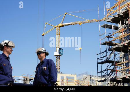 Travailleurs de la construction sur site avec grue en arrière-plan. Banque D'Images