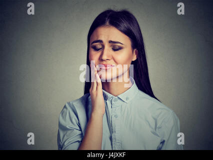 Femme avec couronne de dents sensibles souffrant de douleur problème touchant l'extérieur de la bouche à part isolé sur fond gris. L'émotion négative Banque D'Images