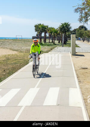 Une femme touring cyclist riding sur une piste cyclable sur la plage près de Malgrat de Mar, Catalogne, Espagne. Banque D'Images