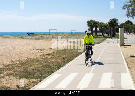 Une femme touring cyclist riding sur une piste cyclable sur la plage près de Malgrat de Mar, Catalogne, Espagne. Banque D'Images