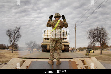 Une batterie A, 2e Bataillon, 4e soldat d'artillerie de la main donne des signaux à un déchargement M270 Système de lance-roquettes multiples véhicule de lancement le 2 décembre 2016, à Fort Sill, Oklahoma Le bataillon revenu récemment d'un champ de l'exercice au centre de formation national, Fort Irwin, en Californie (photo de l'Armée par Cindy MCINTYRE) Banque D'Images