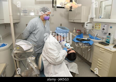 Le s.. Richard Rodriguez, 90e Escadron d'opérations médicales dentaires sous-officier responsable, demande à l'Aviateur Senior Tristan Crosswhite, 90e ODM assistant dentaire, au cours d'un nettoyage des dents à F.E. Warren Air Force Base, Wyo., le 6 avril 2017. Rodriguez a dit qu'il aime travailler avec les aviateurs et fournir une assistance. (U.S. Air Force photo par un membre de la 1re classe Breanna Carter) Banque D'Images