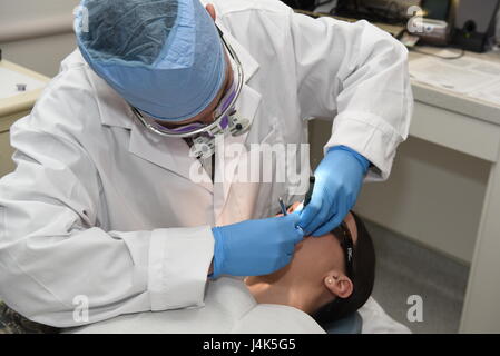 Le s.. Richard Rodriguez, 90e Escadron d'opérations médicales dentaires sous-officier responsable, vérifie les dents d'un patient à F.E. Warren Air Force Base, Wyo., le 6 avril 2017. La clinique dentaire est axée sur l'atteinte de la santé orale supérieure et de la mission de préparation grâce à la sécurité, l'efficacité et des soins axés sur le patient. (U.S. Air Force photo par un membre de la 1re classe Breanna Carter) Banque D'Images