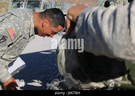 L'Adjudant-chef 3 Carlos Morales, un surveillant de l'entretien avec la 110e compagnie de maintenance Support, Massachusetts Army National Guard, vous permet un flux d'eau d'un buffle d'eau verser sur sa tête à Fort Irwin, en Californie le 3 mai 2017. Au cours d'une rotation de trois semaines au Centre National d'entraînement, les soldats de la 110ème ont été appelé pour un accident impliquant un buffle qui a dû être vidé afin de récupérer le véhicule c'était attaché. Sur un jour de près de 100 degrés dans le désert de Mojave, ont profité de cette et utilisé l'eau de refroidir en buvant de la st Banque D'Images