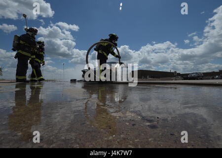 Les membres de l'Tinker l'incendie et d'urgence, 72e Escadron de génie civile, travailler ensemble pour éteindre un incendie le 4 mai 2017, Tinker Air Force Base, Texas. William flexibles Vert-La roue de la voiture et le bas pendant que le Capitaine David Jones, à gauche, et Aaron Simpson, l'arrière-plan, se distingue par d'observateurs. La panne mécanique du véhicule mis au point et a pris feu près de l'Oklahoma City Air Logistics Complexs' building 9001. (U.S. Air Force photo/Greg L. Davis) Banque D'Images