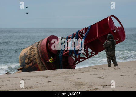 Le Sgt. 1re classe Chris Richards de la Connecticut National Guard se prépare à grimper au sommet d'une 12 000 livres de bouées échouées, le mardi 9 mai 2017, près de Chatham, Massachusetts. Il a joint les élingues de levage à un hélicoptère CH-47 Chinook qui a levé la bouée de la plage. (U.S. Photo de la Garde côtière canadienne par le maître de 3e classe Andrew Barresi) Banque D'Images