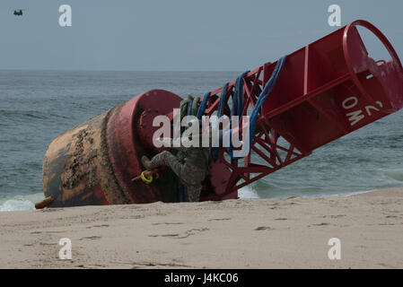 Le Sgt. 1re classe Chris Richards de la Connecticut National Guard se prépare à grimper au sommet d'une 12 000 livres de bouées échouées, le mardi 9 mai 2017, près de Chatham, Massachusetts. Il a joint les élingues de levage à un hélicoptère CH-47 Chinook qui a levé la bouée de la plage. (U.S. Photo de la Garde côtière canadienne par le maître de 3e classe Andrew Barresi) Banque D'Images