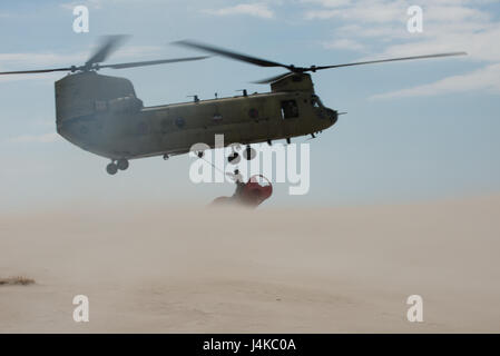 Le Sgt. 1re classe Chris Richards de la Connecticut National Guard attache un 12 000 livres à la bouée échouée sur un hélicoptère CH-47 Chinook, le mardi 9 mai 2017, près de Chatham, Massachusetts. Le Chinook a levé la bouée de la plage et a apporté à l'étranger où le Chêne garde-côte l'a pris. (U.S. Photo de la Garde côtière canadienne par le maître de 3e classe Andrew Barresi) Banque D'Images