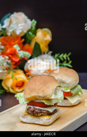 Délicieux petit fromage gourmet burgers fabriqués à partir de viande bovine avec des ingrédients frais, placés sur des plateaux en bois Banque D'Images