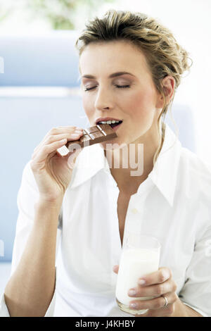 Femme, jeune, chocolat babillard, mordre, verre, tenez, lactée portrait , portrait de femmes, de 20 à 30 ans, célibataire, blonde, serrures, poil long, le mode de vie, la consommation, la tentation, la dévotion, avec délectation, avec dévouement, passion, sensuellement, à l'intérieur, à la maison, l'agréable sensation de bien-être, doux, avec douceur, douceur, schokoladig, chocolat, manger, verre, lait, boisson, les yeux fermés, profitez de Banque D'Images