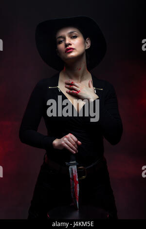 Fille avec un énorme couteau sanglant, rouge fond de fumée Banque D'Images