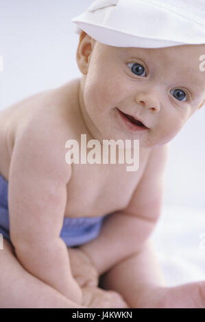 Bébé, s'asseoir, caps, cap, voir l'enfant, petit appareil photo, 5 mois, bébé, couleur des yeux bleu, couleurs vives, sourire, observer, l'attention, les culottes de plastique, à l'intérieur, gondolé, la conception, le développement, les sens, la vue, l'enfance, l'innocence, la délicatesse, la gaieté, l'intérêt, Banque D'Images