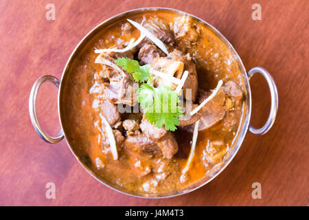 Une chèvre mouton curry rouge préparé dans un bol en acier/laiton. Banque D'Images