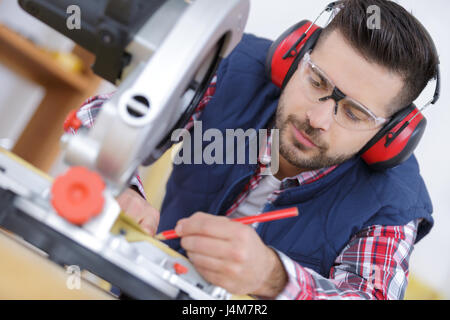 Beau carpenter en des lunettes de planche de mesure Banque D'Images