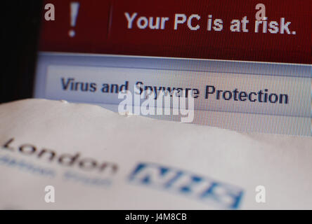 Le rendez-vous du patient une lettre d'un London NHS Hospital, à côté d'un message d'alerte de virus et de logiciel espion sur un ordinateur portable à un écran d'accueil à Londres, à la suite d'une cyber-attaque majeure sur les systèmes informatiques du NHS. Banque D'Images